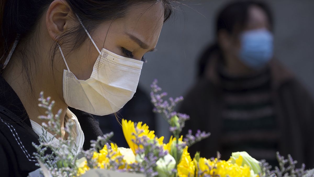 امرأة تحمل الزهور تكريما لضحايا الوباء في ووهان - 2020/04/04