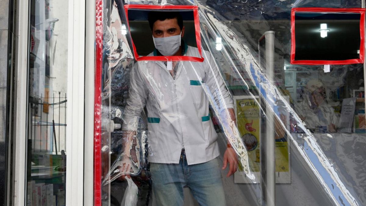 صيدلي يرتدي كمامة قرب باب مغطى بالبلاستيك لتجنب العدوى في الدار البيضاء 27 مارس 2020