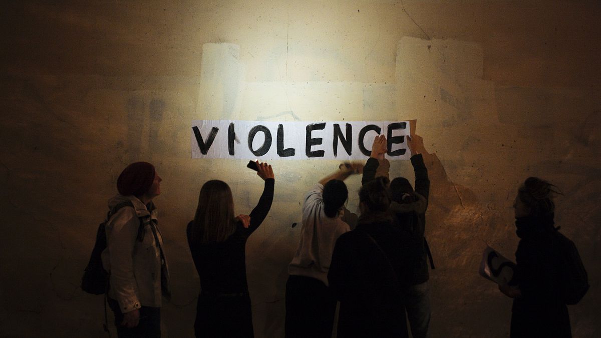 A group of women paste the word "violence" onto a street wall, part of a protest to draw attention to domestic violence, Paris, France, October 2019.
