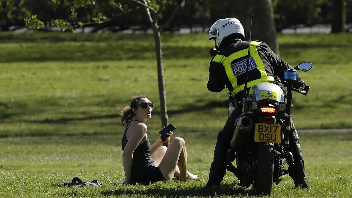 Полицейский просит жительницу Лондона не нарушать карантин. 