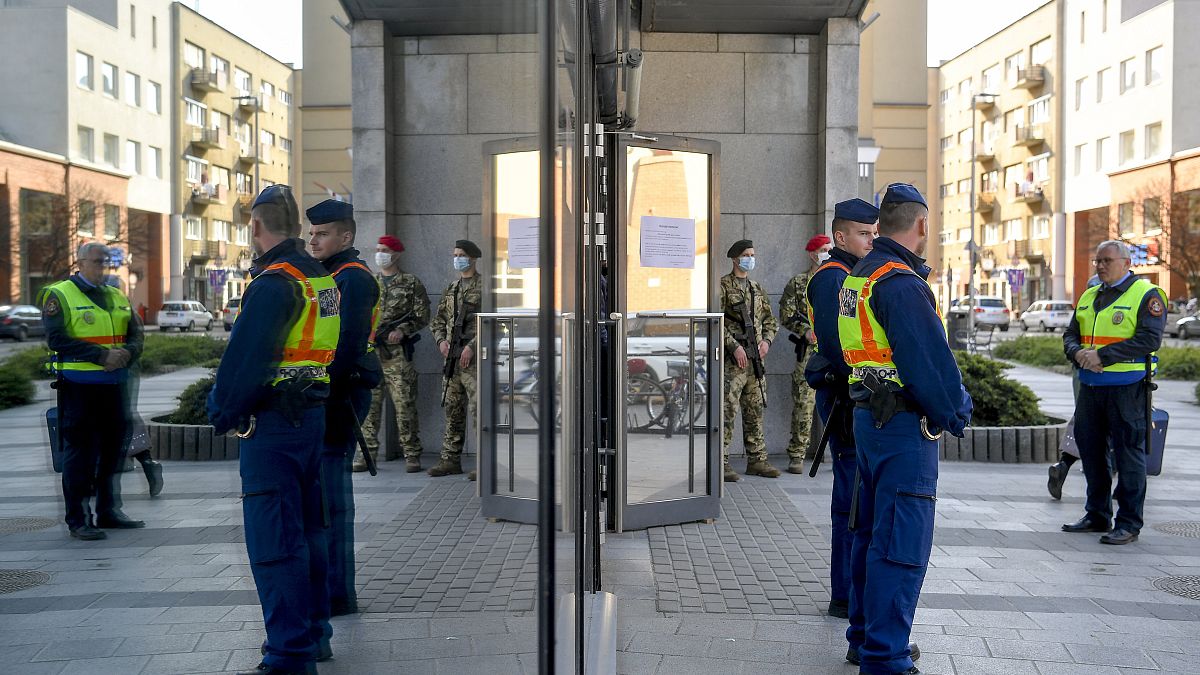 Hungarian policemen and soldiers stand guard at an entrance to the Great Market of Debrecen, Hungary