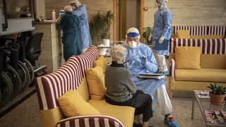 Foto scattata il 1 aprile 2020: un cooperante della Ong spagnola Brazos Abiertos parla con un'anziana prima di un tampone in una casa di riposo