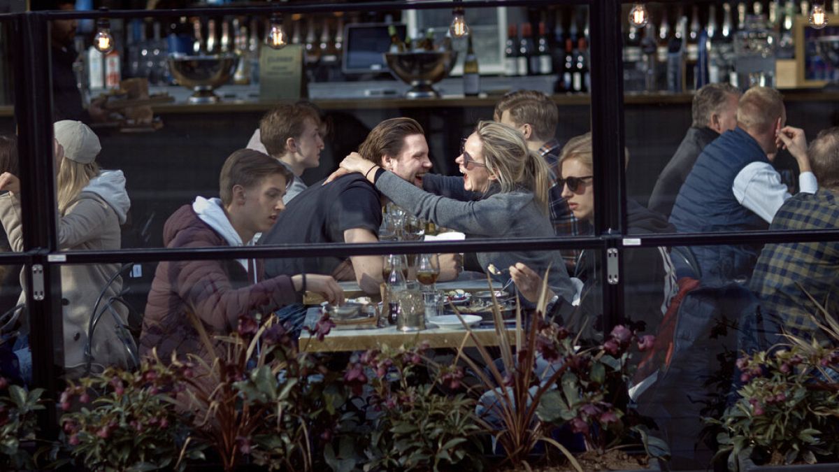 A couple hug and laugh as they have lunch in a restaurant in Stockholm, Sweden, Saturday, April 4, 2020