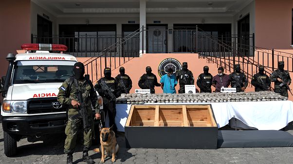 Two members of the Mara 18 gang are escorted by members of the National Force Against Gangs next to drug packages Two members of the Mara 18 gang are escorted by members of the National Force Against Gangs next to drug packages