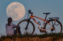 A cyclist stops to watch the Supermoon come up in Sieversdorf, eastern Germany on April 7, 2020. (Photo by Patrick Pleul / dpa / AFP) / Germany OUT