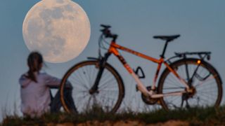 A cyclist stops to watch the Supermoon come up in Sieversdorf, eastern Germany on April 7, 2020. (Photo by Patrick Pleul / dpa / AFP) / Germany OUT