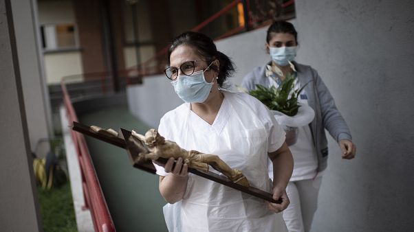 A nurse from a elderly home holds a crucifix on April 10, 2020 in Manta, near Cuneo, northwestern Italy, as part of a Good Friday's Way of the Cross (Via Crucis)