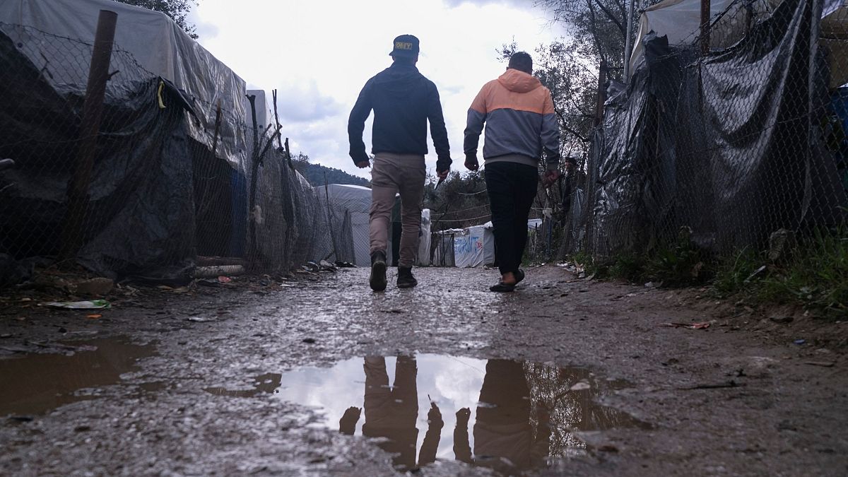 Migrants walk past makeshift tents outside the perimeter of Moria refugee camp