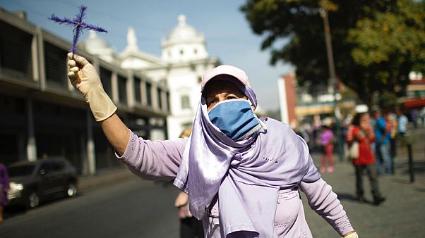 A woman holds up a cross as she tries to follow a statue of Jesus passing by during Holy Week in Caracas, Venezuela, April 8, 2020 A woman holds up a cross as she tries to follow a statue of Jesus passing by during Holy Week in Caracas, Venezuela, April 8, 2020