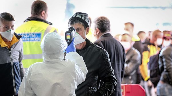 A Romanian seasonal worker has his temperature checked outside the airport in Cluj A Romanian seasonal worker has his temperature checked outside the airport in Cluj