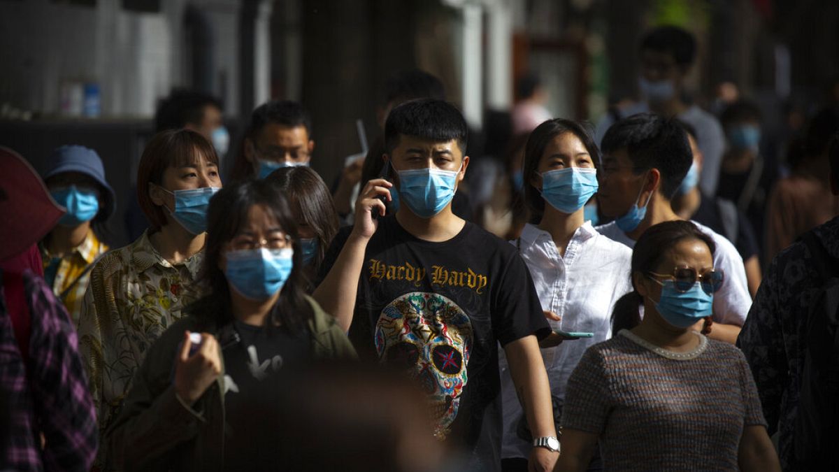 أشخاص يرتدون كمامات للحماية من انتشار فيروس كورونا، في شارع تسوق للمشاة في بكين، السبت 16 مايو 2020. 