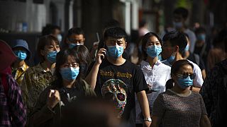 أشخاص يرتدون كمامات للحماية من انتشار فيروس كورونا، في شارع تسوق للمشاة في بكين، السبت 16 مايو 2020.