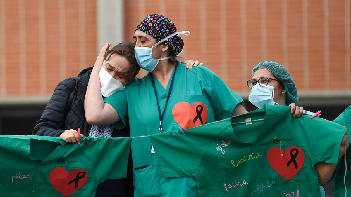 Healthcare workers (R) confort the wife of Esteban, a male nurse that died of the coronavirus