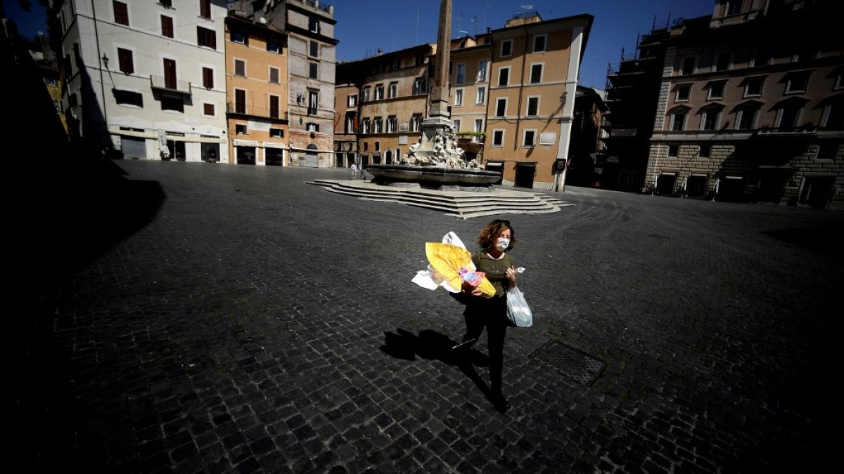 A woman carries her shopping and an Easter egg- Rome, on April 11, 2020