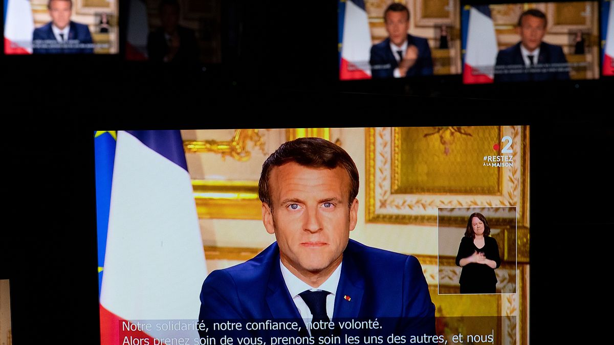 French President Emmanuel Macron is seen on multiple monitors in Paris, as he speaks from the Elysee Palace during a televised address to the nation on April 13, 2020.