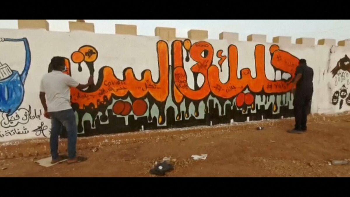 مجموعة من الشباب ينظفون شوارع العاصمة السودانية الخرطوم وجدرايات تدعو للبقاء في المنازل للوقاية من وباء كورونا