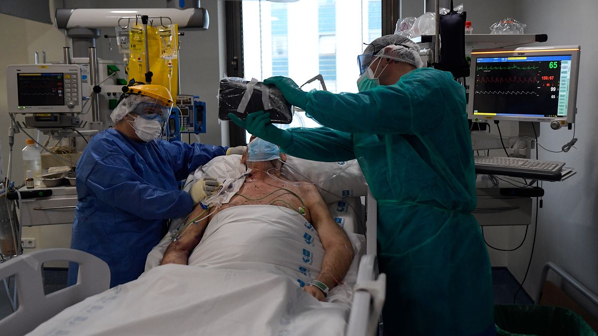 Des soignants tiennent une tablette devant un patient atteint du coronavirus COVID-19 pour qu'il appelle ses proches, à l'hôpital Ramon y Cajal de Madrid