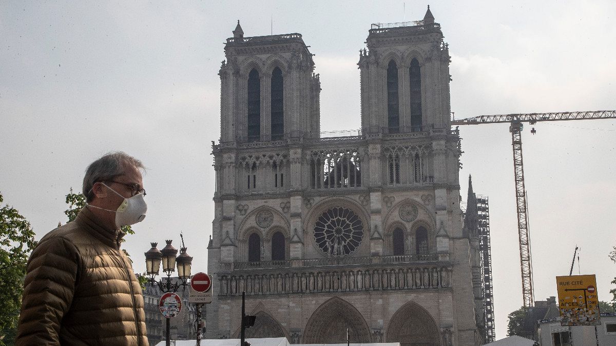 Um homem de máscara passa diante da catedral de Notre-Dame, em Paris
