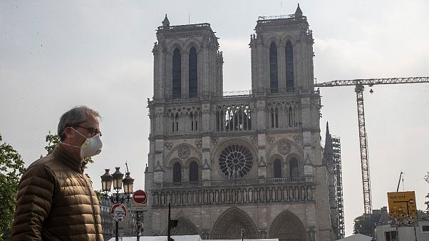Um homem de máscara passa diante da catedral de Notre-Dame, em Paris Um homem de máscara passa diante da catedral de Notre-Dame, em Paris