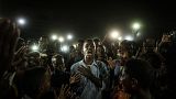 People chant slogans as a young man recites a poem, illuminated by mobile phones, before the opposition's direct dialogue with people in Khartoum on June 19, 2019