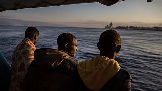 Men who were rescued off the Libyan coast, watch the city of Messina from the deck of the Open Arms rescue vessel as the ship enters the port located on the island of Sicily