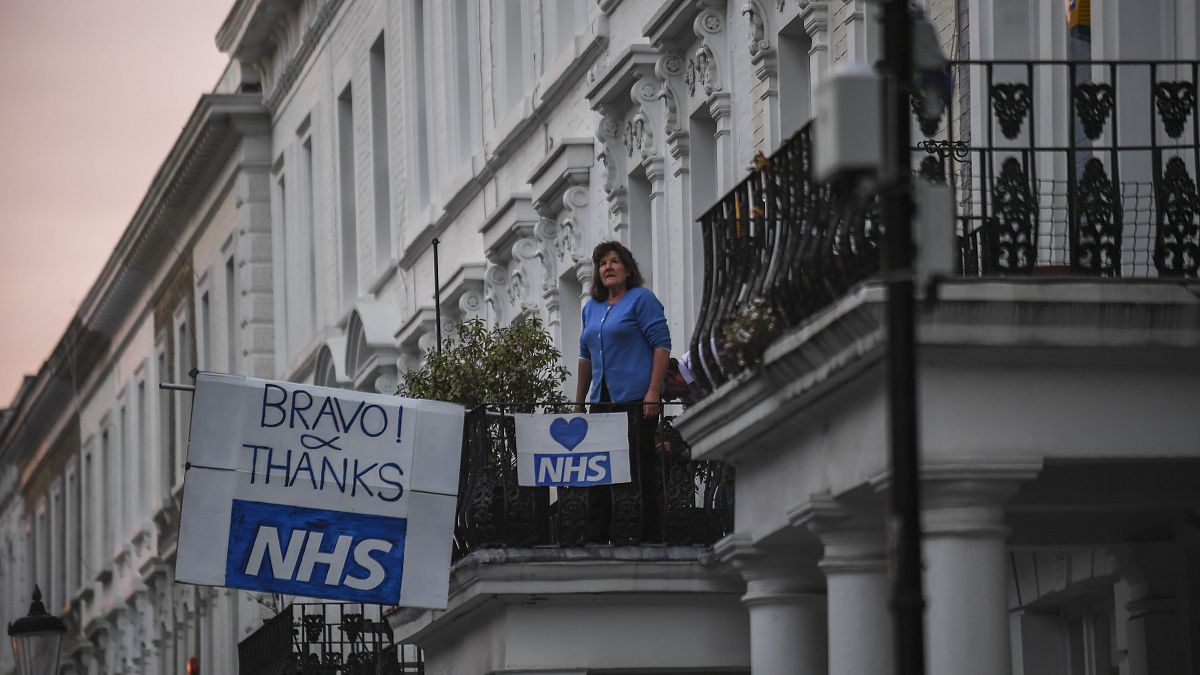 سيدة تقف على شرفة أحد مراكز الخدمات الطبية الوطنية في بريطانيا 
