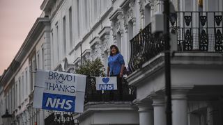 سيدة تقف على شرفة أحد مراكز الخدمات الطبية الوطنية في بريطانيا