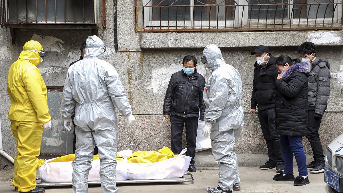 Funeral home workers remove the body of a person suspected to have died from the coronavirus outbreak from a residen tial building in Wuhan, Hubei Province, February 1, 2020.