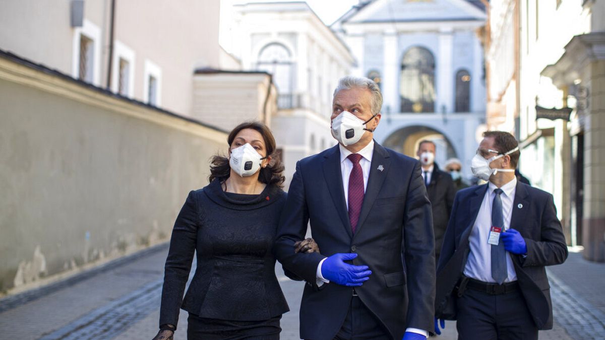 Lithuania's President Gitanas Nauseda and his wife Diana Nausediene, left, wearing face masks after leaving church in Vilnius