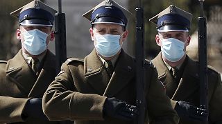 A military guard of honor wear face masks against the spread of the coronavirus by the Unknown Soldier's Tomb in Warsaw, Poland, Thursday, April 16, 2020