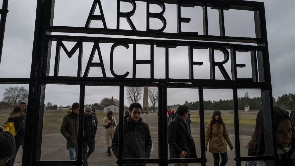 Visitors walk past the gate of the former Sachsenhausen concentration camp