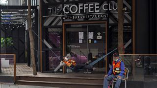 سائق دراجة نارية يأخذ قسطا من الراحة أمام مقهى مغلق بسبب الحجر الصحي المروض في بانكوك-2020/04/14