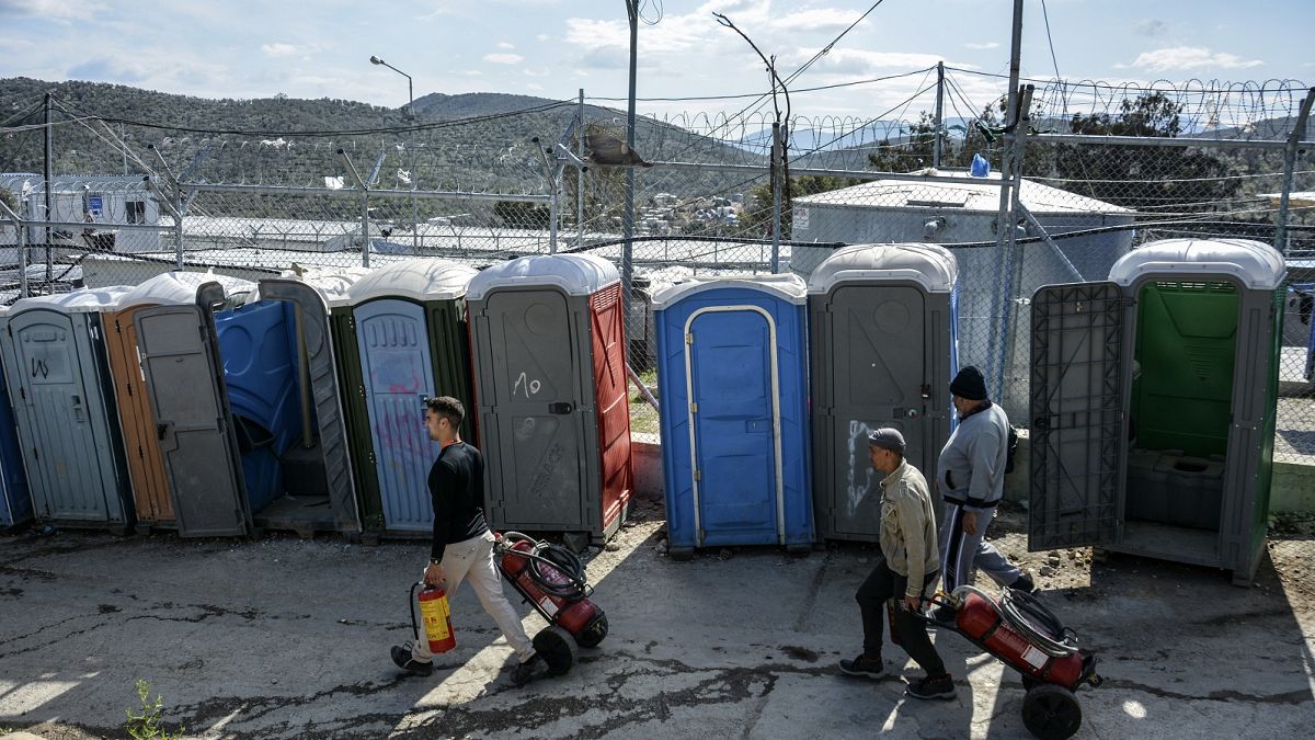 Migrants pull fire extinguishers in Moria refugee camp on the northeastern Aegean island of Lesbos, Greece, Monday, March 16, 2020