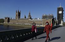 People wear masks as they walk near Britain's Houses of Parliament as it goes back to work, London, Tuesday, April 21, 2020.
