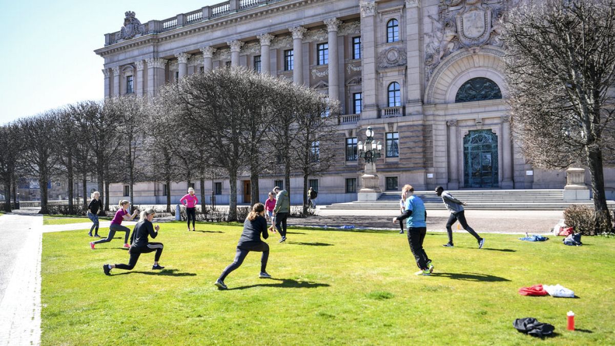 People exercise on a lawn, keeping distance amid the coronavirus disease (COVID-19) outbreak, outside the old parliament building in central Stockholm, Sweden, Tuesday, April 