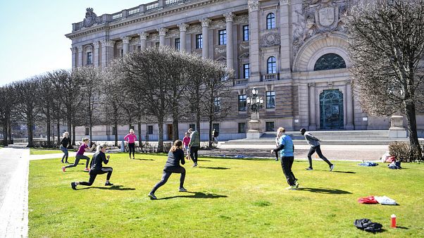 People exercise on a lawn, keeping distance amid the coronavirus disease (COVID-19) outbreak, outside the old parliament building in central Stockholm, Sweden, Tuesday, April 