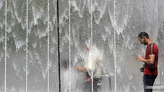 Un uomo si rinfresca vicino a una fontana a Milano, 28/06/2019