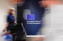 People walk by a sign in English and French in the press room at an EU summit in Brussels on Tuesday, June 28, 2016.