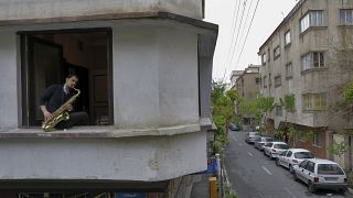 In this Wednesday, April 8, 2020 photo, Mohammad Maleklee, 23, of the National Orchestra of Iran and Tehran Symphony, plays saxophone in his window