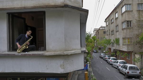 In this Wednesday, April 8, 2020 photo, Mohammad Maleklee, 23, of the National Orchestra of Iran and Tehran Symphony, plays saxophone in his window In this Wednesday, April 8, 2020 photo, Mohammad Maleklee, 23, of the National Orchestra of Iran and Tehran Symphony, plays saxophone in his window