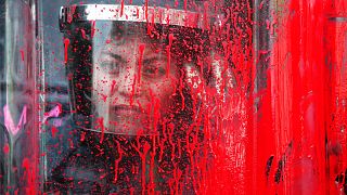 A police officer stands behind her riot shield covered in red paint during an International Women's Day march in Mexico City's main square, Sunday, March 8, 2020.