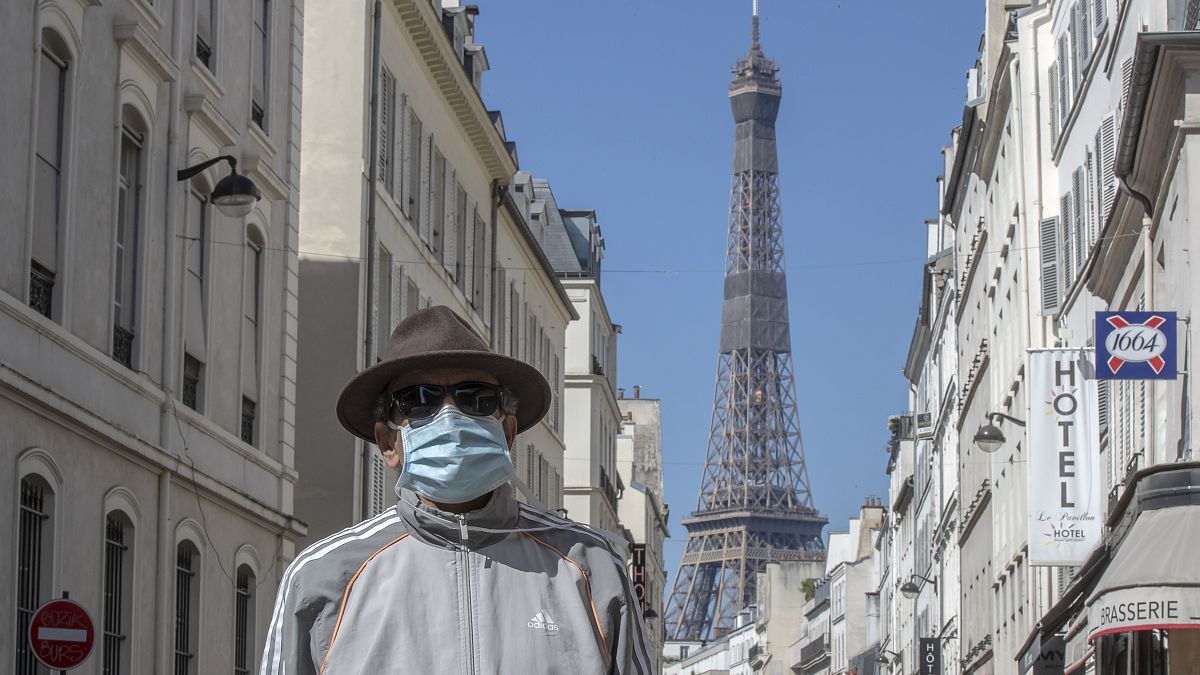 A man wears a mask to protect against the spread of the coronavirus walk in a street close to the Eiffel Tower in Paris, Sunday, April 26, 2020. 