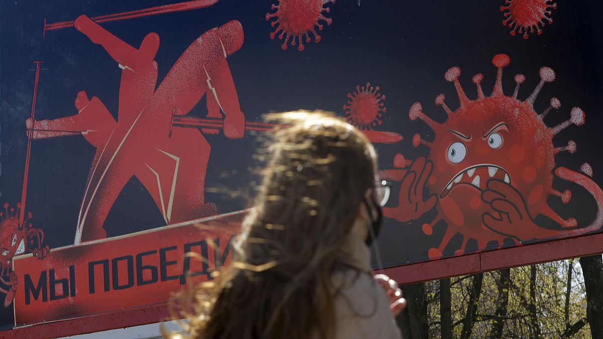 A woman walks past an advertising placard depicting the coronavirus and words reading "We will win" in Minsk, Belarus, Wednesday, April 22, 2020.