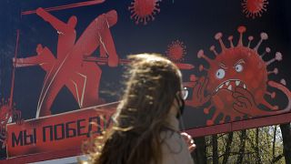 A woman walks past an advertising placard depicting the coronavirus and words reading "We will win" in Minsk, Belarus, Wednesday, April 22, 2020.