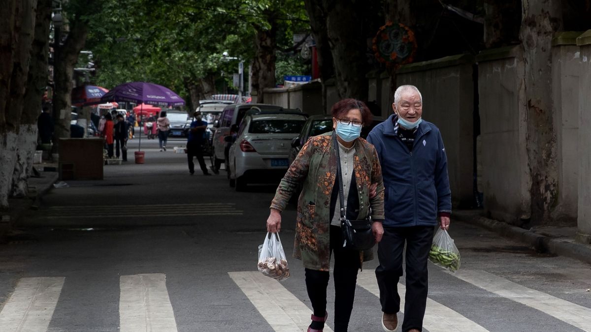 Çin'in Hubei bölgesindeki Vuhan şehrinde maske takmış yaşlı bir çift alışverişten dönüyor