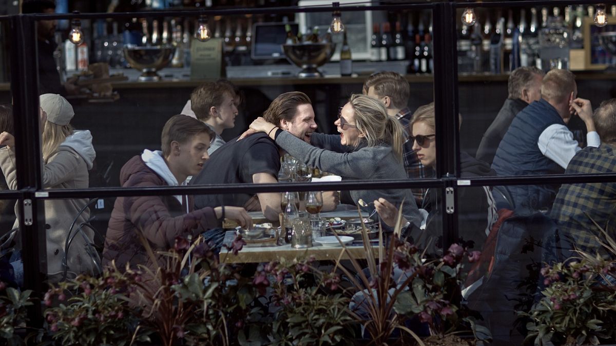 A couple hug and laugh as they have lunch in a restaurant in Stockholm, Sweden, Saturday, April 4, 2020
