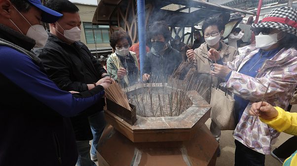 Creyentes budistas con máscaras faciales para ayudar a proteger contra la propagación del nuevo coronavirus
