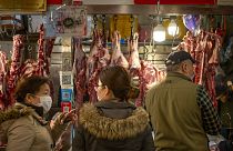 People wear face masks as they shop for meat at a market in Beijing, Saturday, March 14, 2020