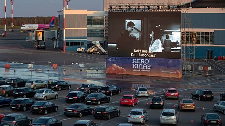 People sit in their cars watching a movie at a new drive-in cinema at the airport in Vilnius, Lithuania on April 29, 2020.