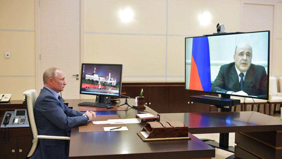 Russian President Vladimir Putin listens to Prime Minister Mikhail Mishustin, displayed on TV screen on the right, during their meeting via teleconference - 30th April 2020 